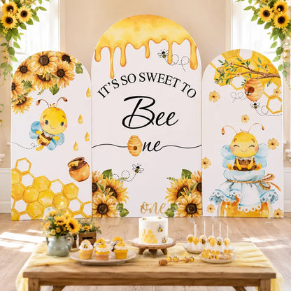Three-piece bee first birthday arch backdrop covers set with cute honey bees, sunflowers, honeycomb, beehive and It's So Sweet to Bee One lettering.