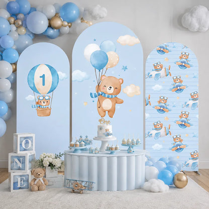 Three-piece blue first birthday arch backdrop covers set with teddy bears, airplanes, hot air balloon, clouds and number one design.