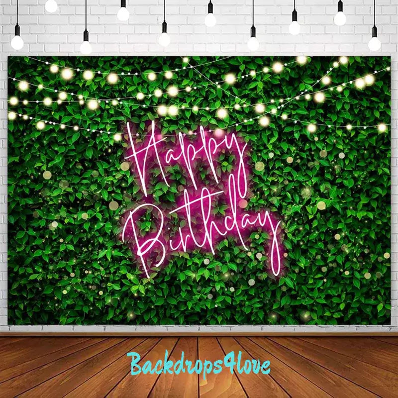 A vibrant birthday backdrop featuring lush green leaves with a pink neon 'Happy Birthday' sign, accented with glowing string lights. Ideal for garden-themed parties or stylish indoor celebrations.