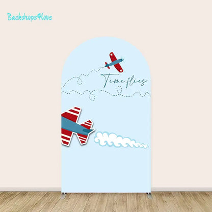 Light blue arch backdrop with a blue and red airplane flying and the text 'Time Flies' written in the sky with dotted lines.