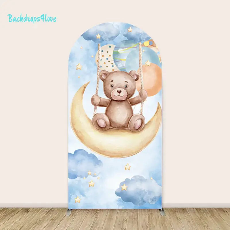 Left arch with a teddy bear sitting on a crescent moon swing surrounded by watercolor clouds and glowing stars.