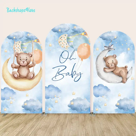 Dreamy baby shower arch trio with blue watercolor skies, golden stars, a bear on a moon swing, and a center arch reading ‘Oh Baby’ with balloons.